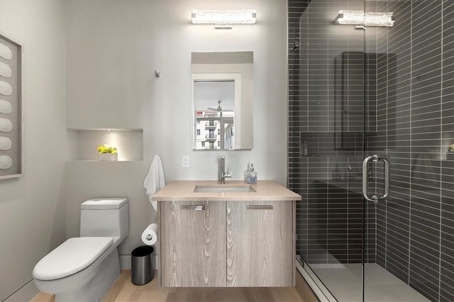 bathroom with hardwood / wood-style floors, vanity, an enclosed shower, and toilet