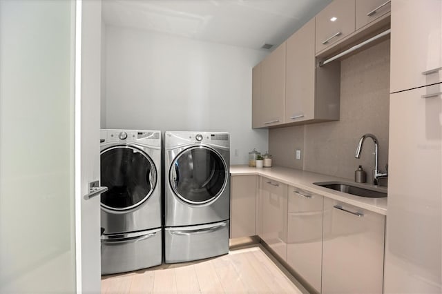 laundry area with cabinets, washing machine and dryer, and sink