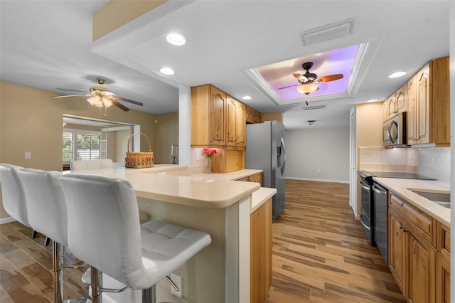 kitchen featuring a kitchen bar, light wood-type flooring, stainless steel appliances, and kitchen peninsula