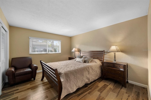 bedroom featuring wood tiled floor, baseboards, and a closet