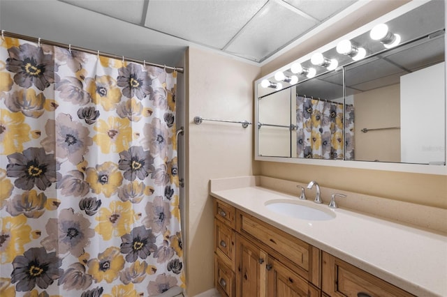 bathroom with a stall shower, a drop ceiling, and vanity