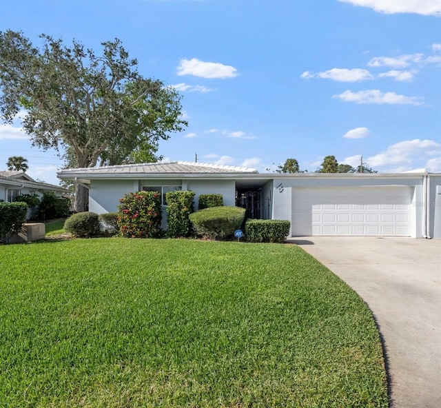 single story home featuring a garage, driveway, a front yard, and stucco siding