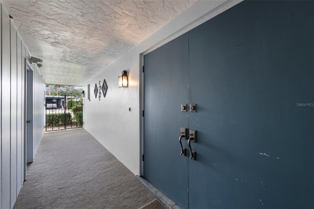 hall featuring a textured ceiling and carpet flooring