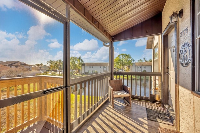 sunroom with a wealth of natural light, a water view, and lofted ceiling