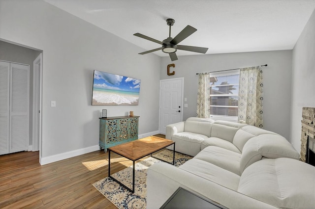 living room with a fireplace, hardwood / wood-style flooring, ceiling fan, and lofted ceiling