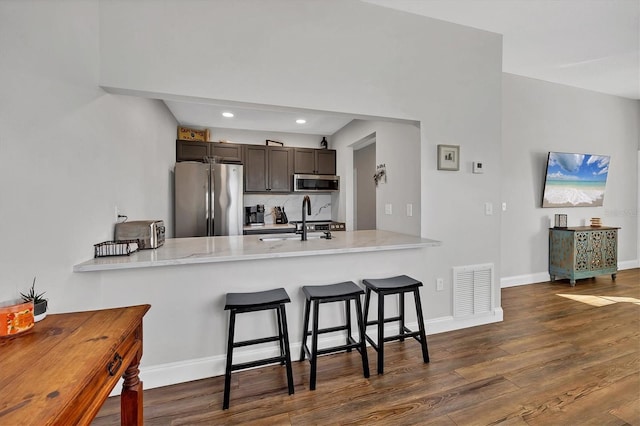 kitchen featuring sink, kitchen peninsula, stainless steel appliances, and dark brown cabinetry