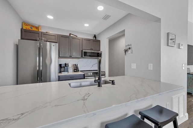 kitchen featuring a breakfast bar area, kitchen peninsula, hardwood / wood-style flooring, and appliances with stainless steel finishes