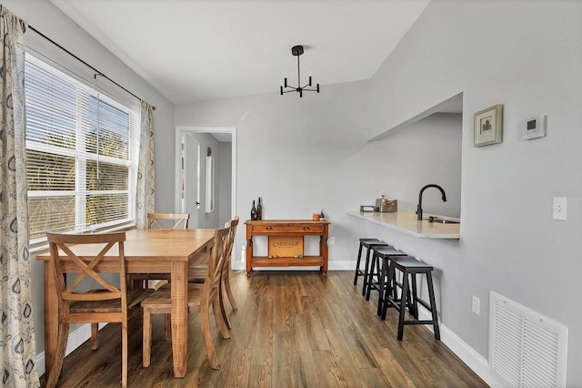 dining space with sink, dark wood-type flooring, and vaulted ceiling