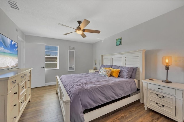 bedroom with ceiling fan, dark hardwood / wood-style flooring, and a textured ceiling