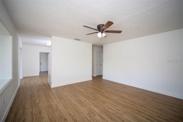 unfurnished room featuring light hardwood / wood-style floors, ceiling fan, and a textured ceiling