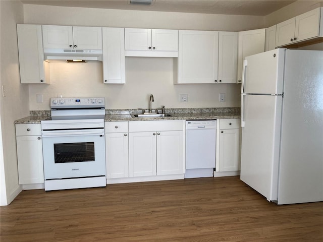 kitchen featuring white appliances, dark wood-type flooring, white cabinets, dark stone counters, and sink