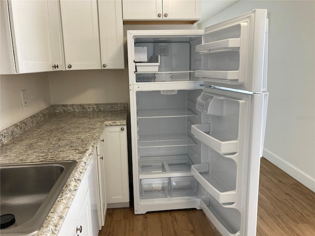 kitchen featuring sink, fridge, wood-type flooring, and white cabinetry