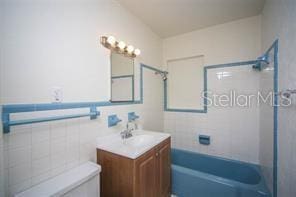 full bathroom with toilet, tiled shower / bath, and vanity