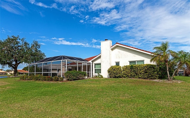 rear view of property featuring glass enclosure and a lawn