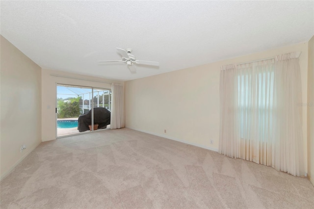 unfurnished room featuring a textured ceiling, light colored carpet, and ceiling fan