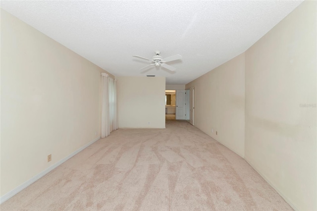 empty room featuring ceiling fan, light colored carpet, and a textured ceiling