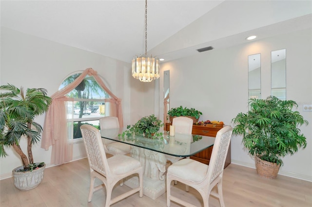 dining room with an inviting chandelier, lofted ceiling, and light hardwood / wood-style flooring