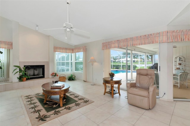 living room with ceiling fan, light tile patterned floors, a tile fireplace, and lofted ceiling