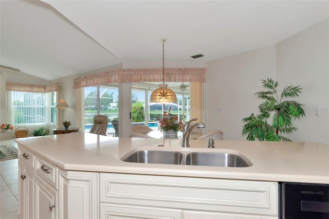 kitchen featuring sink, light tile patterned floors, pendant lighting, vaulted ceiling, and white cabinets