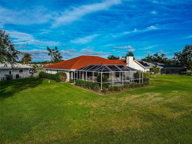 back of property featuring glass enclosure and a yard