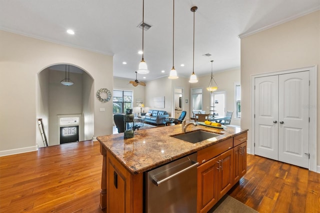 kitchen featuring sink, light stone counters, an island with sink, stainless steel dishwasher, and hanging light fixtures