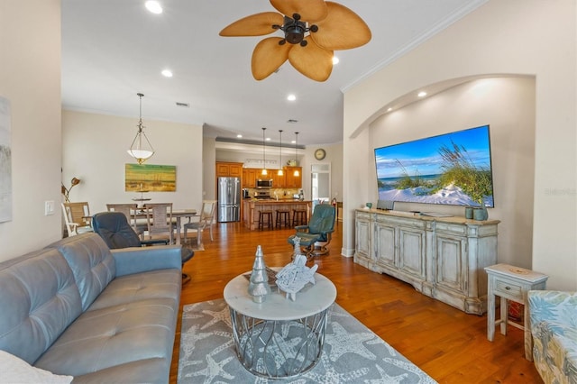 living room featuring ceiling fan, crown molding, and wood-type flooring