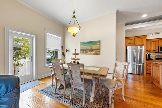 dining area with ornamental molding and light wood-type flooring