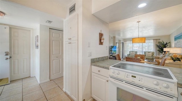 kitchen featuring pendant lighting, light tile patterned floors, electric range, and white cabinets