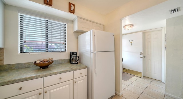 kitchen featuring white cabinetry, white fridge, and light tile patterned flooring