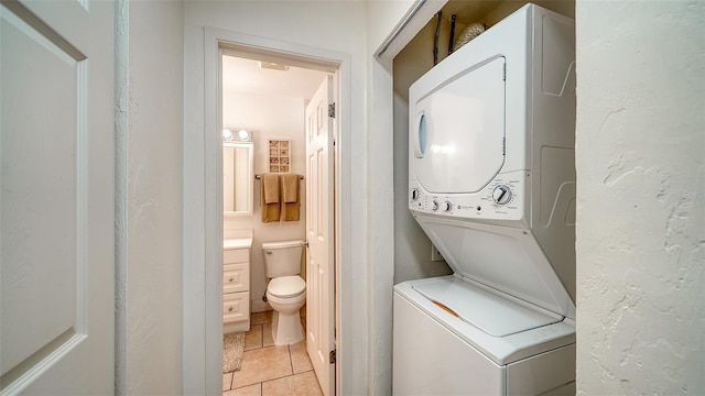 washroom featuring stacked washer and dryer and light tile patterned floors