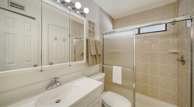 bathroom featuring vanity, toilet, and a shower with shower door