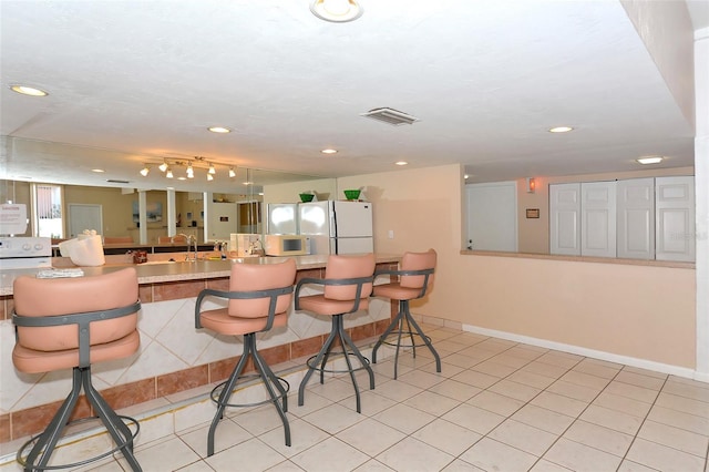 bar featuring white appliances and light tile patterned floors