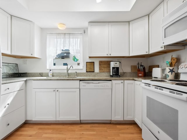 kitchen featuring light stone counters, white appliances, sink, light hardwood / wood-style floors, and white cabinetry