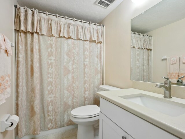 bathroom with tile patterned floors, vanity, a textured ceiling, and toilet