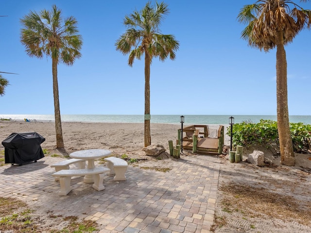 view of patio featuring area for grilling, a water view, and a view of the beach