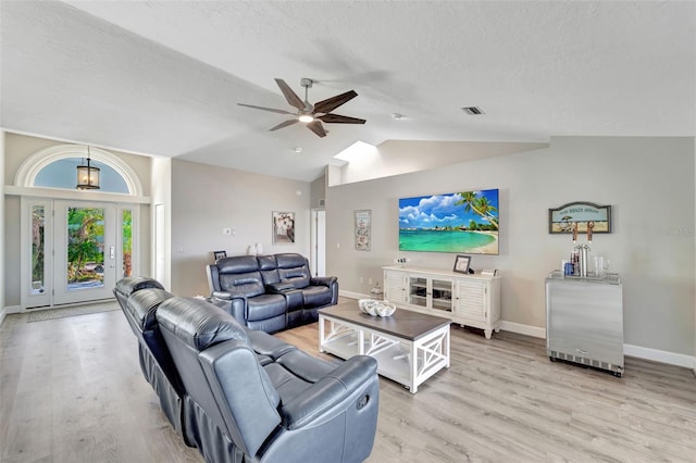 living room featuring a textured ceiling, light hardwood / wood-style floors, ceiling fan, and lofted ceiling