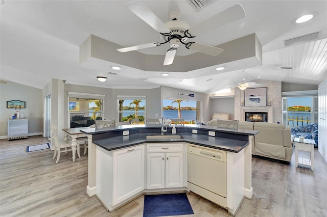 kitchen with white dishwasher, white cabinets, sink, ceiling fan, and a fireplace