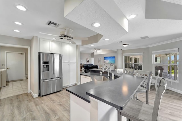 kitchen featuring stainless steel refrigerator with ice dispenser, a textured ceiling, ceiling fan, sink, and white cabinetry