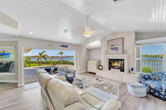 living room featuring a high end fireplace, vaulted ceiling, ceiling fan, a water view, and light hardwood / wood-style floors