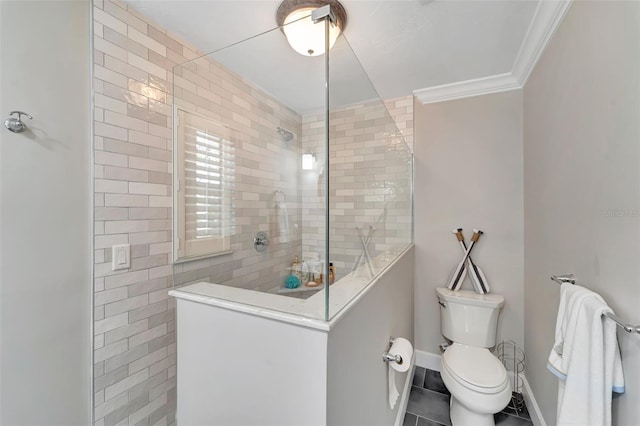 bathroom featuring tile patterned floors, toilet, a tile shower, and ornamental molding