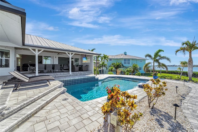 view of swimming pool featuring a patio area, ceiling fan, and a water view