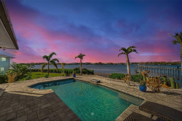 pool at dusk with a water view and a patio