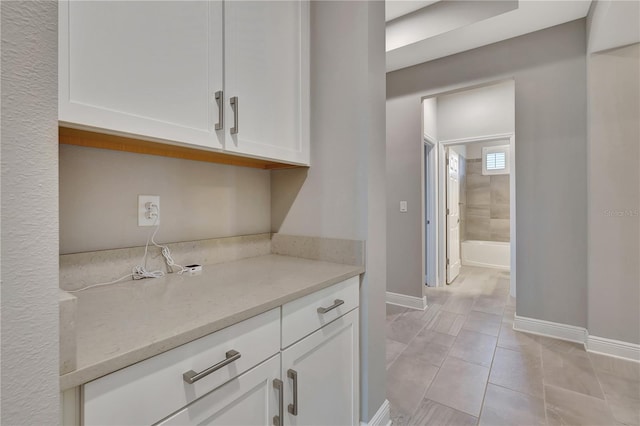 kitchen featuring light tile patterned floors, white cabinets, and light stone counters