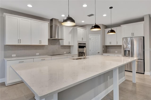 kitchen with white cabinetry, appliances with stainless steel finishes, a spacious island, hanging light fixtures, and wall chimney exhaust hood