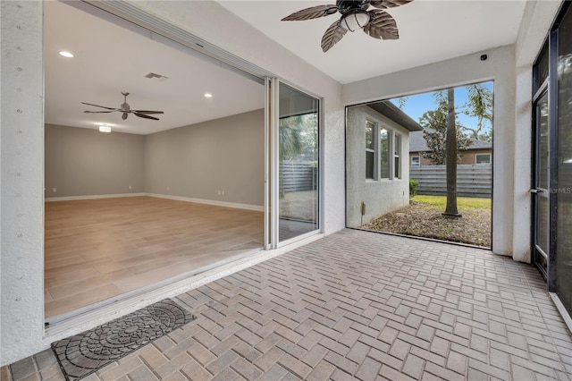 unfurnished sunroom featuring ceiling fan