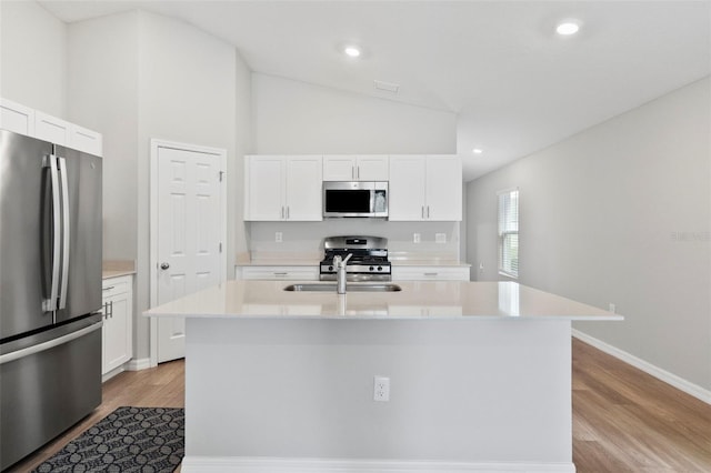 kitchen featuring white cabinets, light wood-type flooring, stainless steel appliances, and a kitchen island with sink