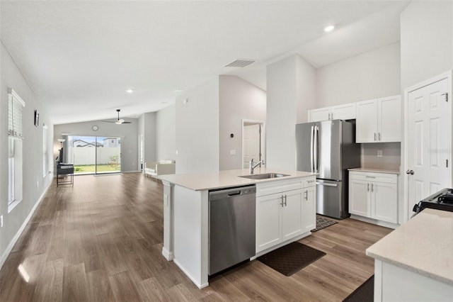 kitchen featuring lofted ceiling, a kitchen island with sink, sink, appliances with stainless steel finishes, and white cabinetry