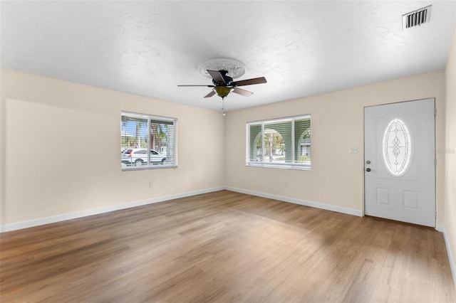 foyer entrance with a wealth of natural light, ceiling fan, and light wood-type flooring