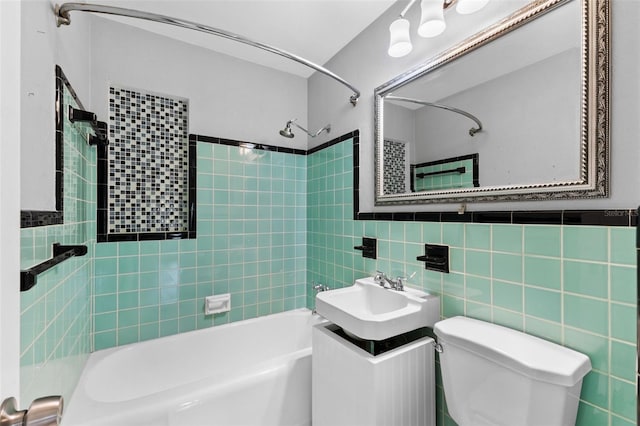 full bathroom with tiled shower / bath, vanity, toilet, and tile walls