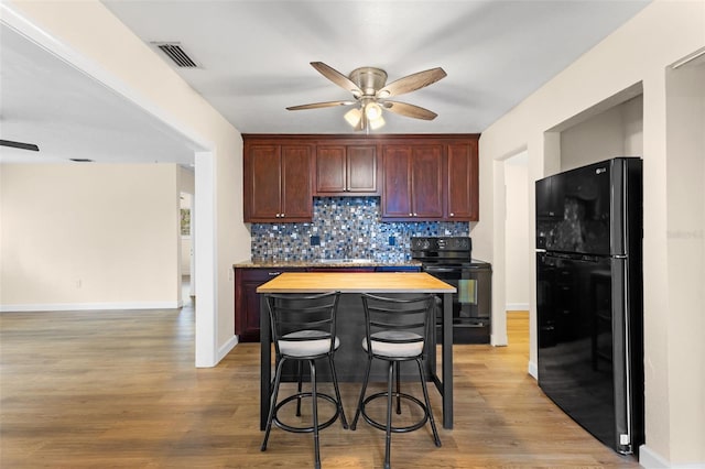 kitchen with ceiling fan, sink, light hardwood / wood-style flooring, butcher block countertops, and black appliances